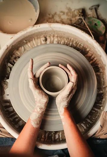 two hands on a pottery wheel making something