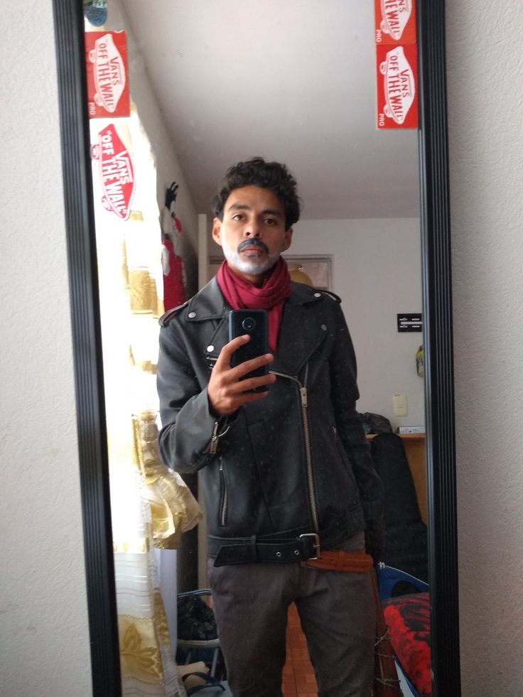 a man standing in front of a mirror looking at his cell phone and taking a selfie