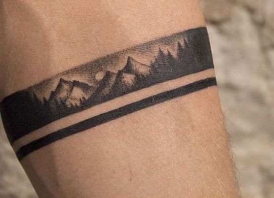 a man's arm with a tattoo on it that has mountains in the background