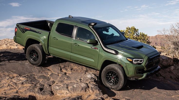 a green truck parked on top of a rocky hill