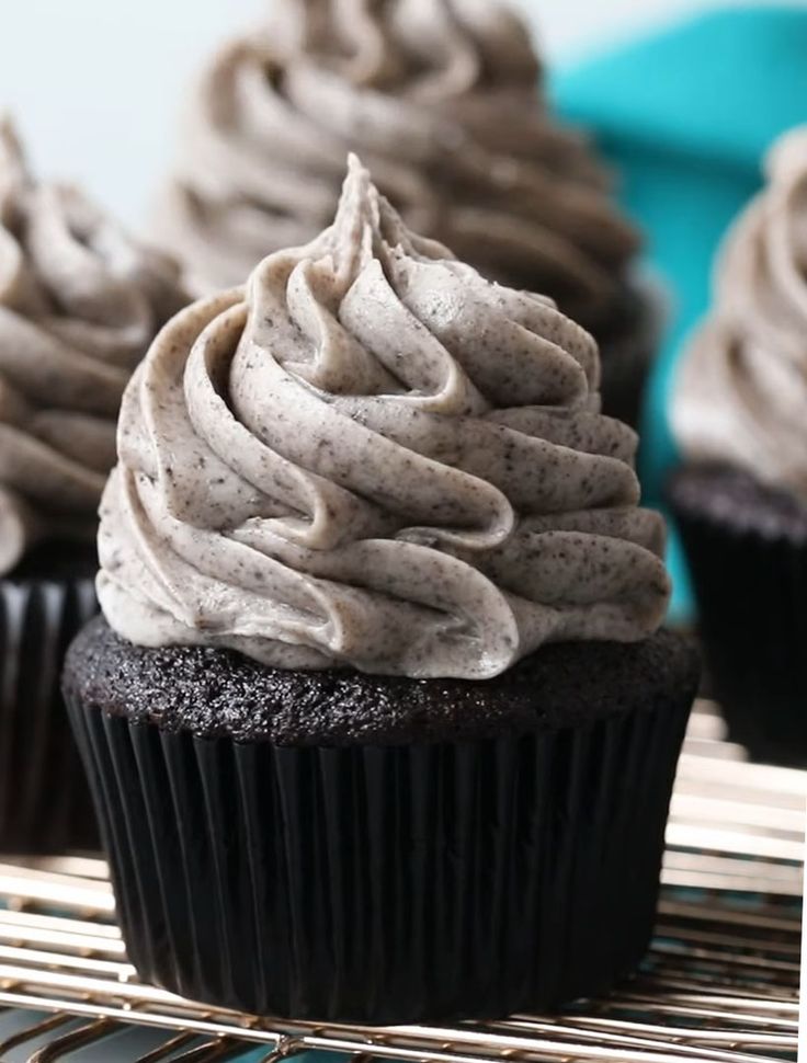 chocolate cupcakes with white frosting sitting on a cooling rack