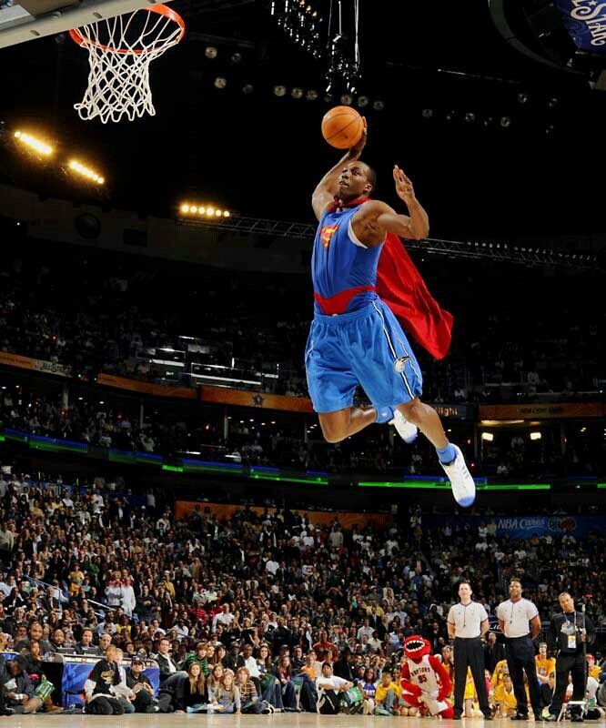 a basketball player jumping up into the air to dunk a ball in front of an audience