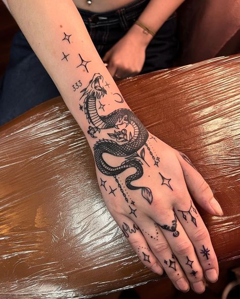 a woman's hand with a dragon tattoo on it and stars around the wrist