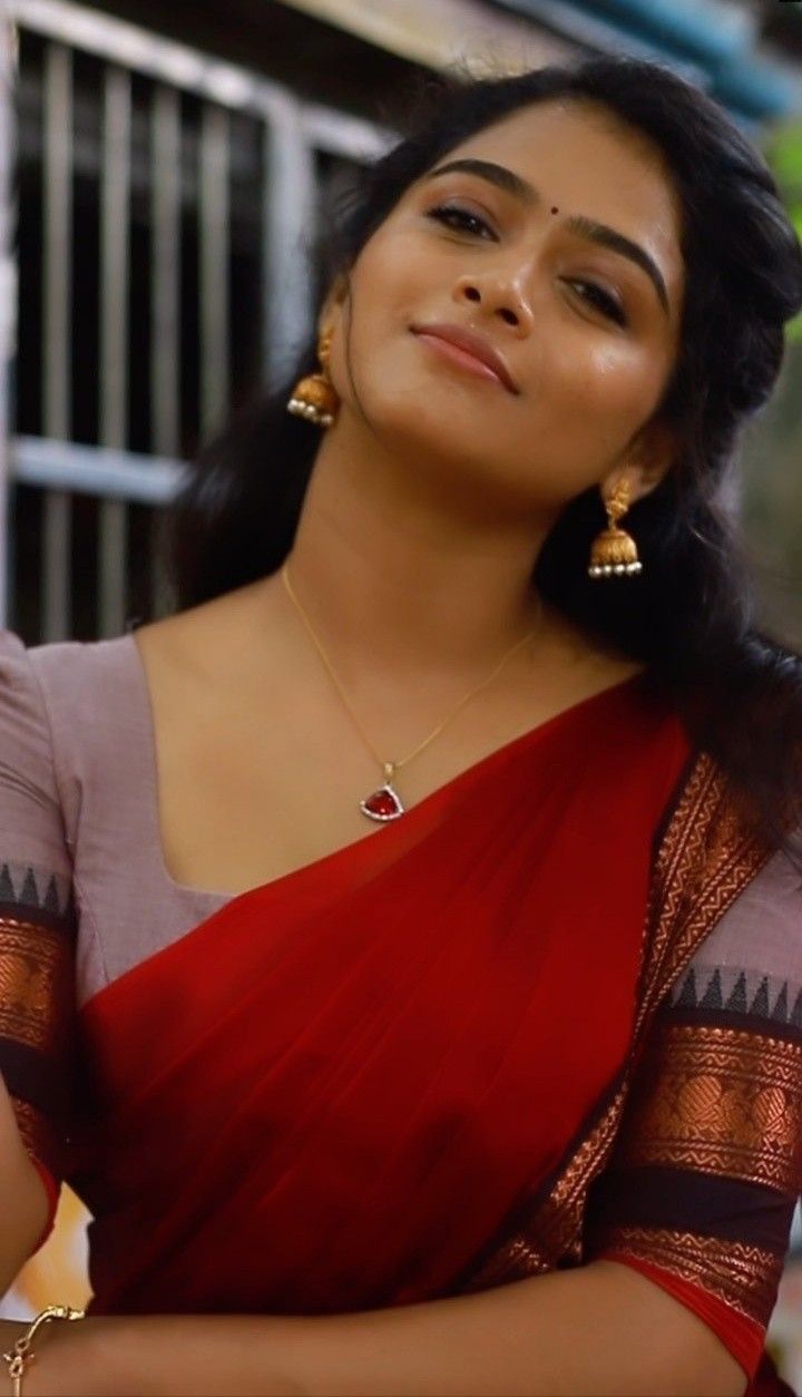 a woman in a red and gold sari with her hands folded on her chest