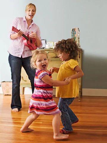 a woman and two children playing with a guitar