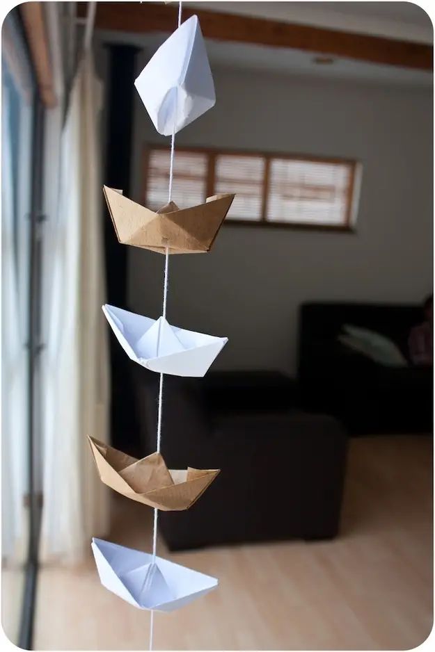 a mobile with paper boats hanging from it