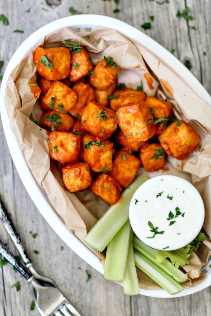 a bowl filled with tater tots and celery next to a fork