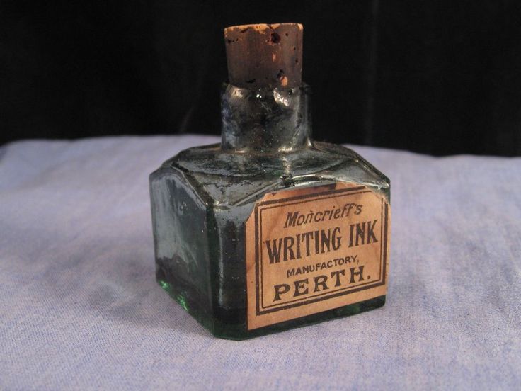 an old bottle with writing ink on it sitting on a blue cloth covered tablecloth