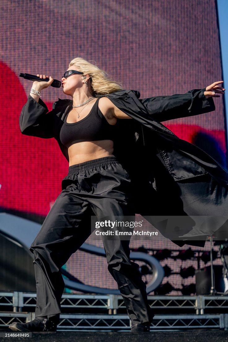 the singer performs on stage at an outdoor music festival in front of a large screen