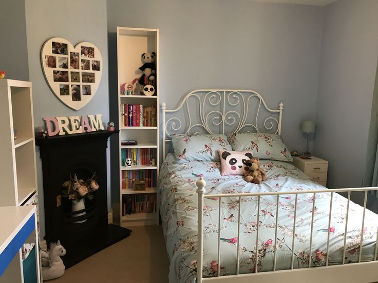 a bedroom with a bed, bookshelf and stuffed animals