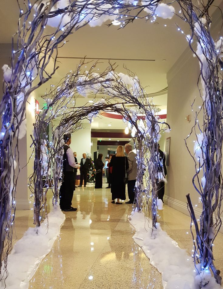 a group of people standing under an archway decorated with lights and branches in a lobby