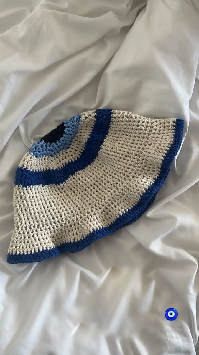 a crocheted blue and white hat laying on top of a bed