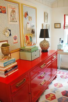 a red dresser sitting next to a bed in a bedroom