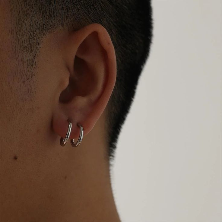 a close up of a person with ear piercings on their ears and behind them is a man's head