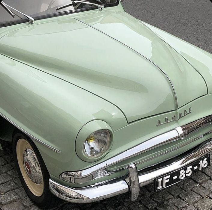 an old green car is parked on the street