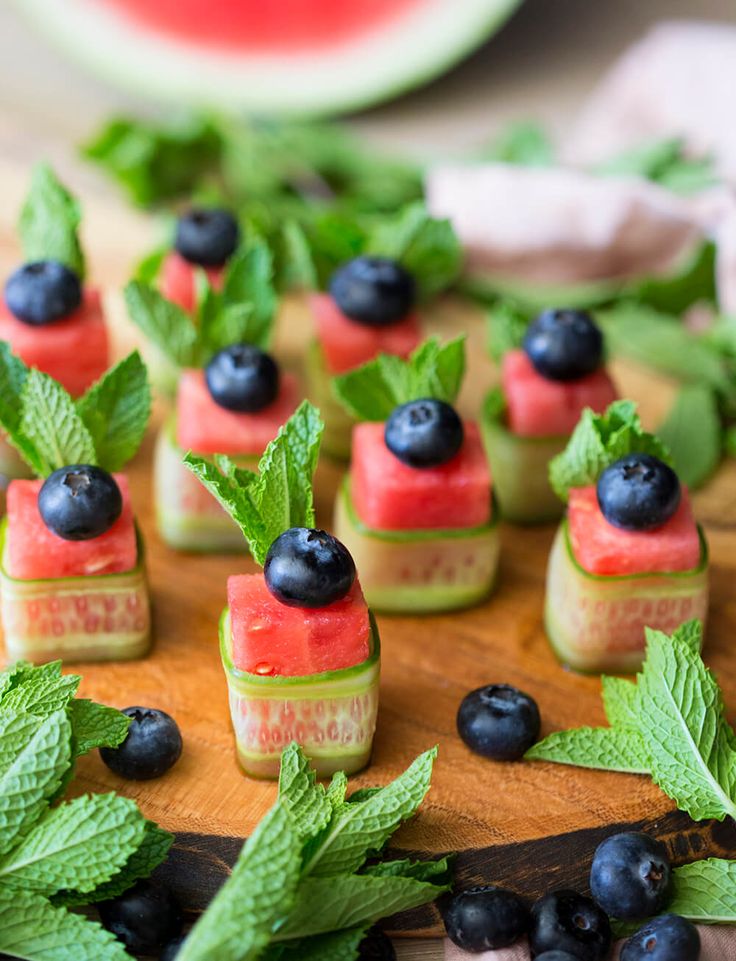 watermelon slices with blueberries and mint leaves on a cutting board, ready to be served