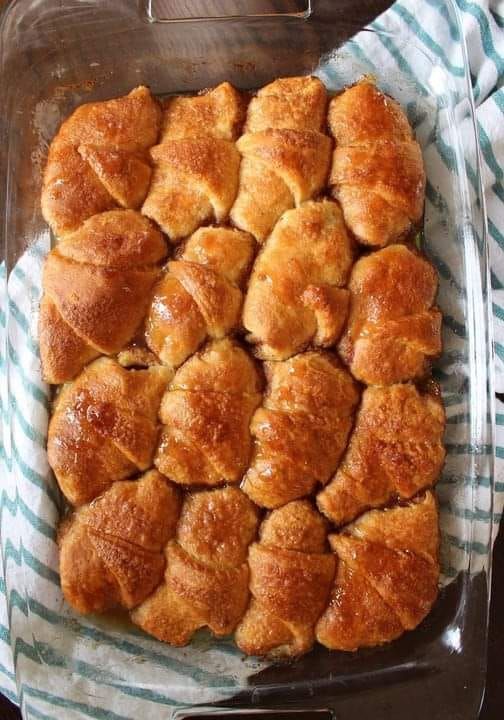 a glass dish filled with croissants sitting on top of a blue and white towel