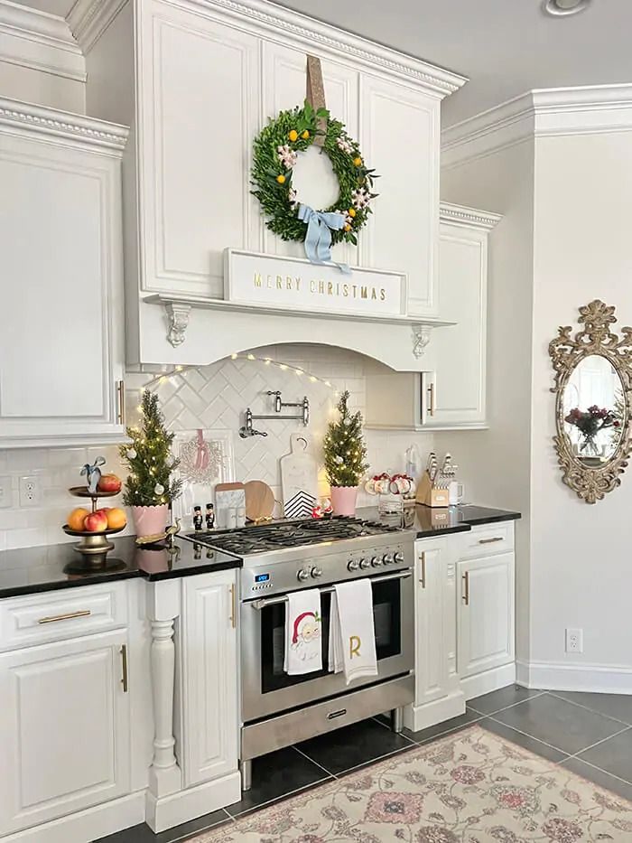 a kitchen decorated for christmas with wreaths on the wall and lights hanging above the stove