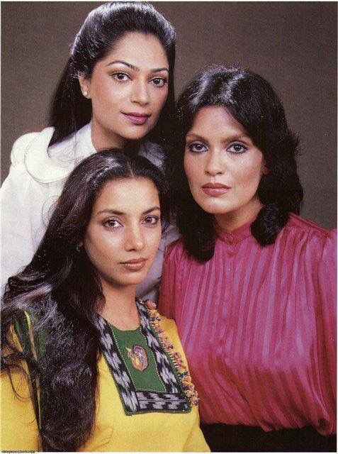 three women standing next to each other in front of a wall