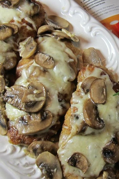 a white plate topped with chicken covered in mushroom toppings and green beans next to a book