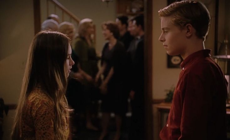 a boy and girl standing next to each other in front of a group of people