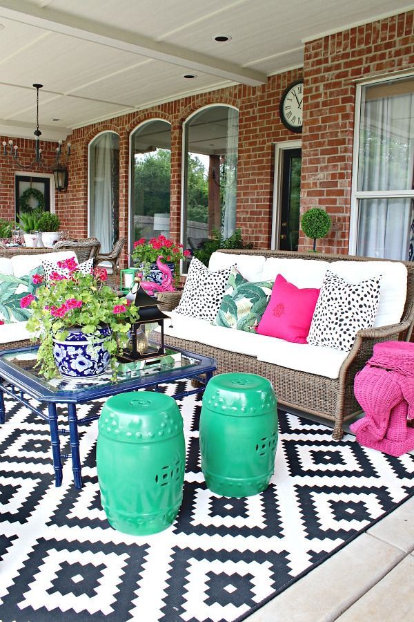 an outdoor living area with couches, tables and potted plants