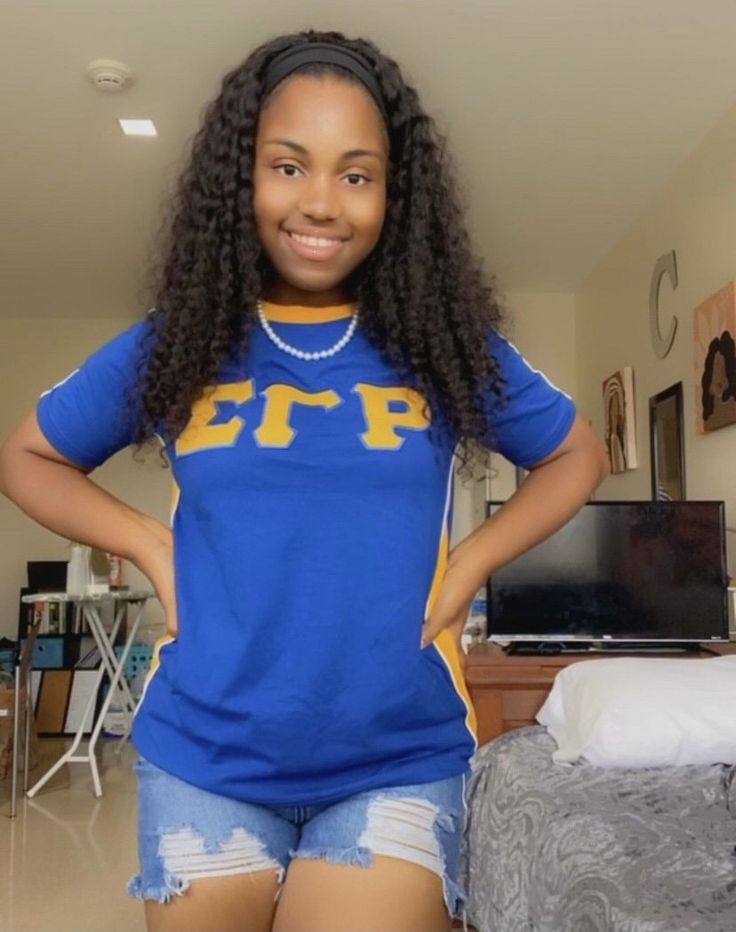 a woman standing in front of a bed wearing shorts and a t - shirt with the letters fpp on it