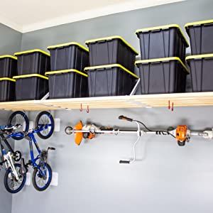 there is a bike and several bins on the shelf in this bicycle storage room