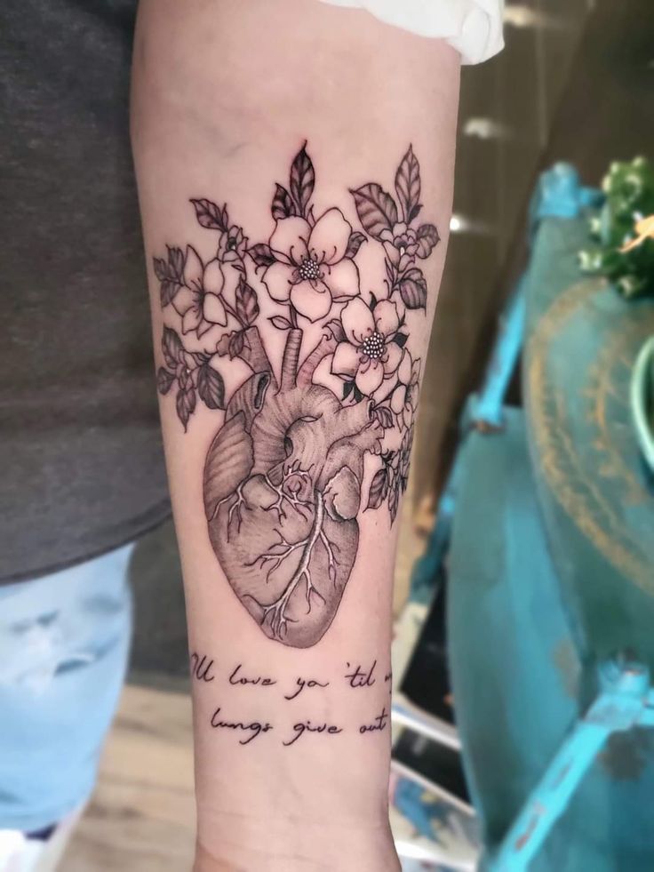 a heart tattoo with flowers on the arm