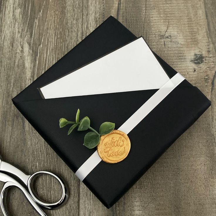 a black and white graduation cap with a gold seal on it, next to scissors