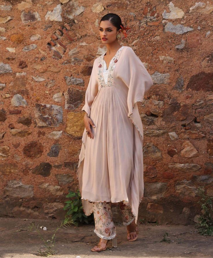 Step into luxury with this embellished kaftan featuring exquisite appliqué work on the neckline, perfectly paired with embellished printed pants. This ensemble marries intricate detailing with vibrant prints, offering a perfect balance of elegance and style. Ideal for special occasions or evenings out, it promises to make a statement with its unique design. Elegant Palazzo Set With Embroidered Neckline, Wedding Pant Set With Dabka On Straight Kurta, Anarkali Kurta With Embroidered Neckline Maxi Length, Anarkali Style Maxi Kurta With Embroidered Neckline, Anarkali Style Kurta With Embroidered Neckline, Anarkali Set With Embroidered Neckline For Eid, Maxi Length Kaftan For Wedding And Navratri, Wedding Kaftan For Navratri In Maxi Length, Elegant Pant Set With Cape Sleeves