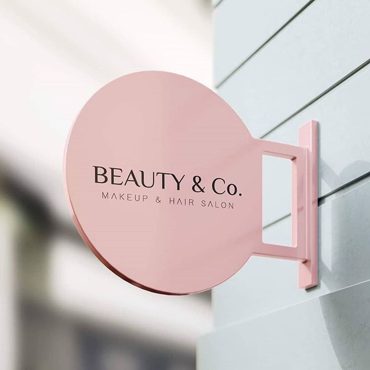 a pink sign on the side of a building that says beauty & co makeup and hair salon