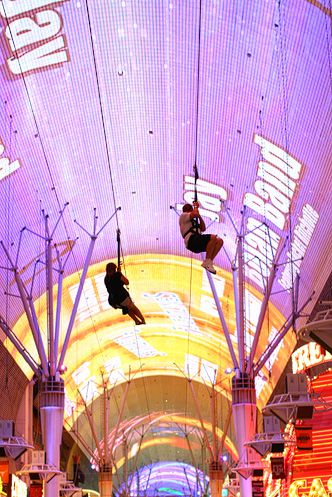 two people are suspended from the ceiling in an indoor shopping mall, while one person is performing aerial acrobatics