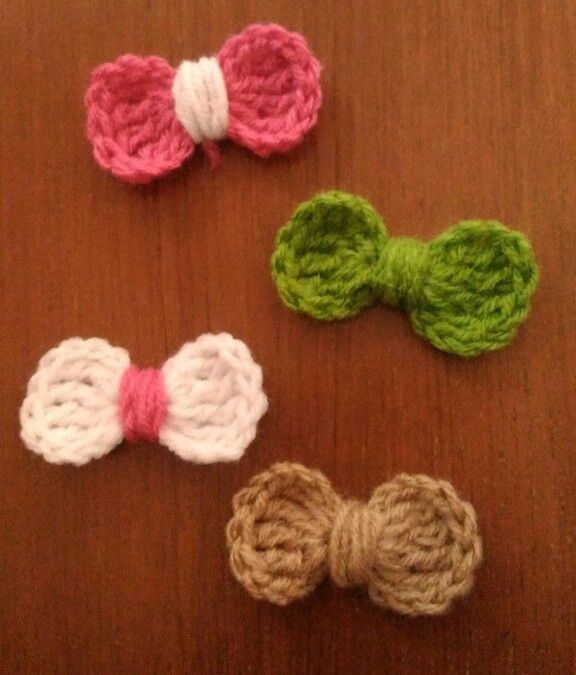 three crocheted bows sitting on top of a wooden table