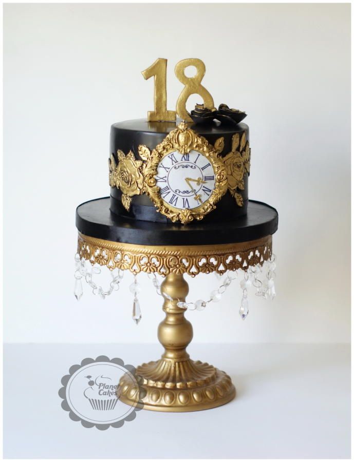 a black and gold cake with a clock on top