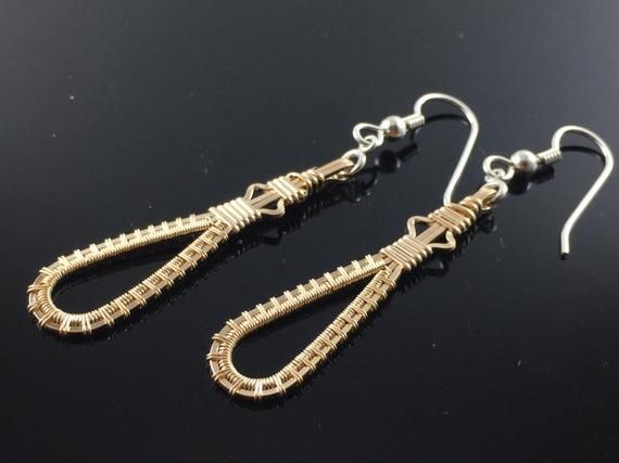 two pairs of earrings on a black surface