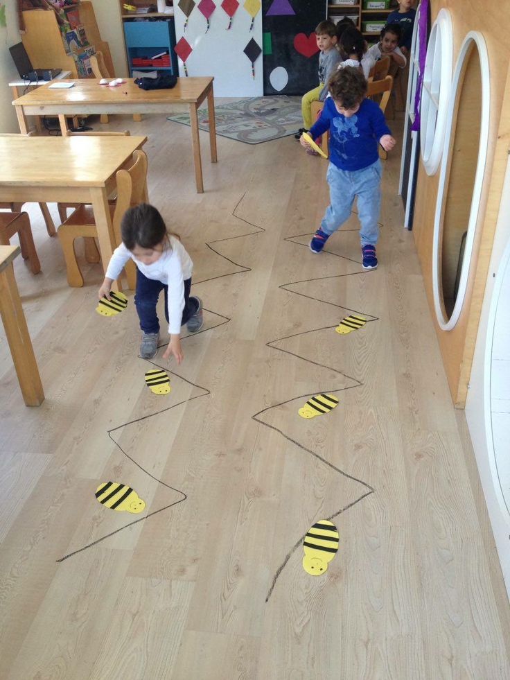 two young children playing with construction paper on the floor in a playroom at school