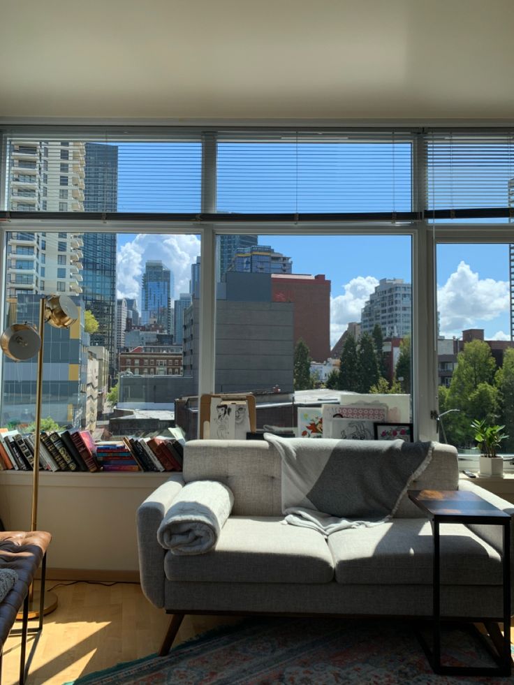 a living room filled with furniture and large windows overlooking the cityscape in the distance