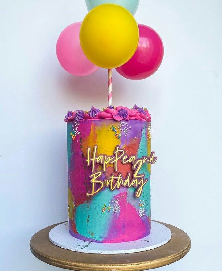 a colorful birthday cake with balloons on top