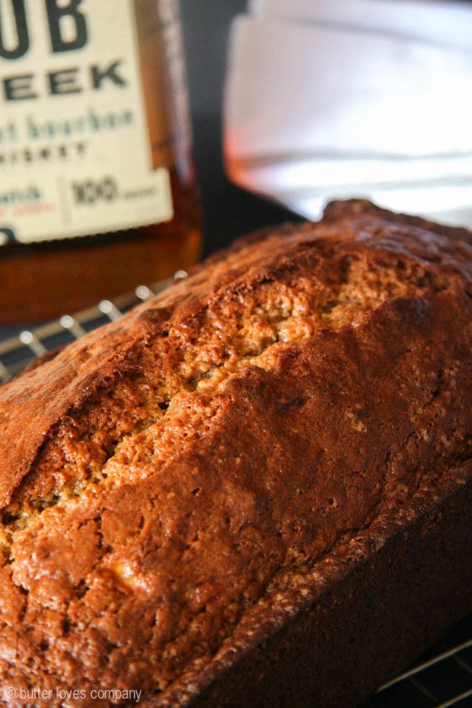 a loaf of bread sitting on top of a cooling rack next to a bottle of bourbon