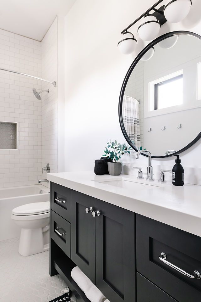 a black and white bathroom with a round mirror