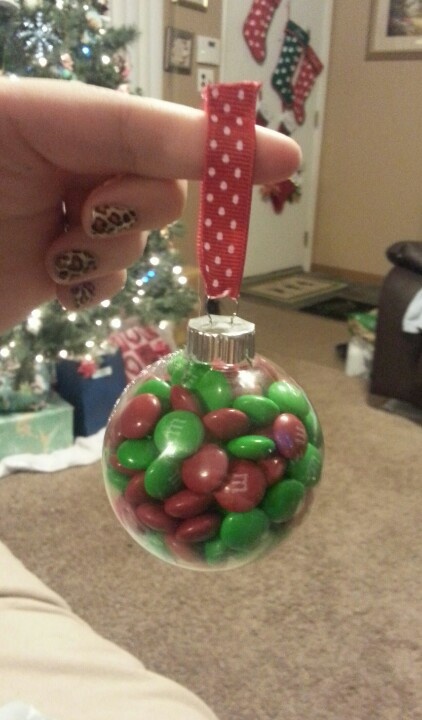 a hand is holding a christmas ornament with candy in the shape of a ball