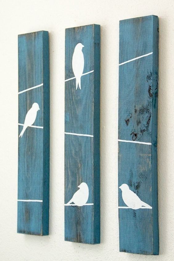 three pieces of wood with birds painted on them, one is blue and the other is white