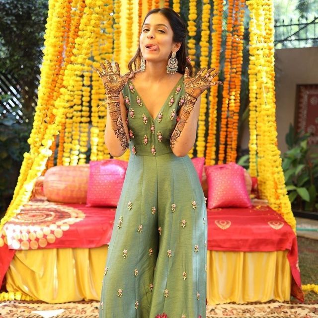 a woman standing in front of a bed with flowers on it and holding her hands up