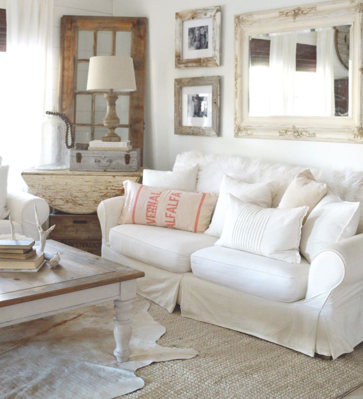 a living room filled with white furniture and pictures on the wall above it's coffee table