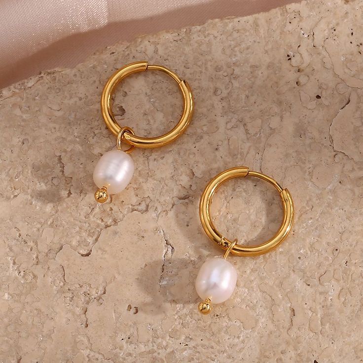 Bring some classic, luxe style to your jewelry box with these stunning Pearl Dangle Gold Hoops! These beautiful hoops feature a pearl drop element that adds a subtle, elegant touch, perfect for pairing with your most stylish outfits. Elevate your look with these timeless stunners! DETAILS & SIZE Sold as a pair Finish: 18K gold plate Materials: 316L Stainless Steel; Faux pearls Measurements: Pearls: approx. 10mm; Hoop diameter: 13mm Hinged hoops with a secure snap post closure Waterproof, tarnish Luxury Earrings, Ringe Gold, Pearl Hoop Earrings, Stylish Earring, Pearl Charms, Stainless Steel Earrings, Gold Hoops, Gold Plated Earrings, Pretty Jewellery