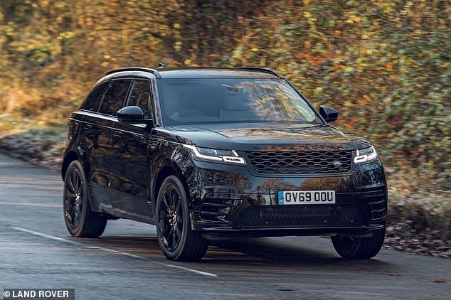 a black range rover driving down a road in front of some bushes and shrubbery