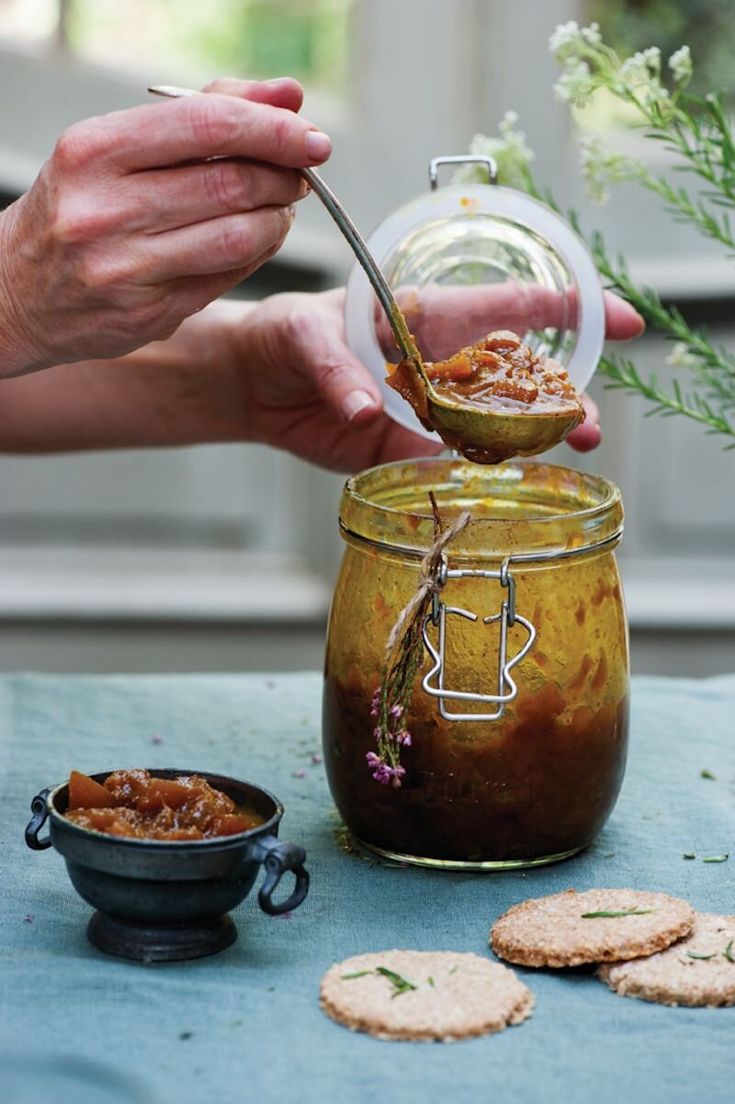 a person spooning food out of a jar with crackers and flowers in the background