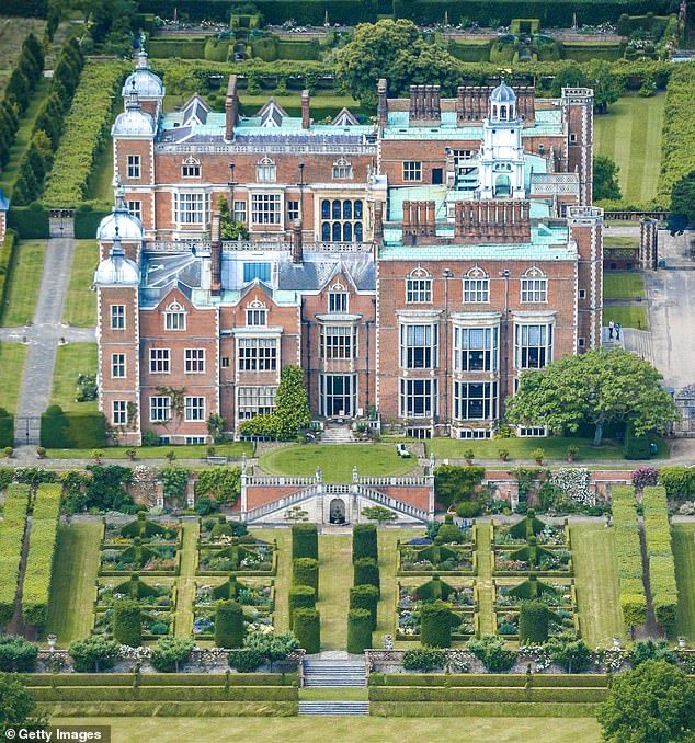 an aerial view of a large brick building surrounded by lush green trees and shrubs in the foreground