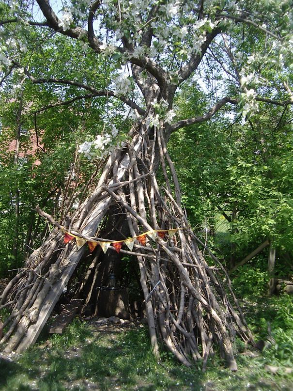 a teepee in the middle of some trees with flags hanging from it's branches